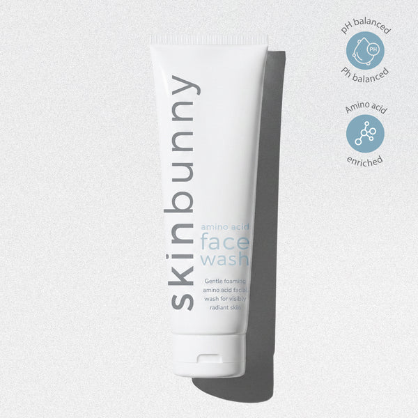A white squeeze tube of skinbunny face wash with grey text, shown on a light grey background with two circular blue icons on the right.